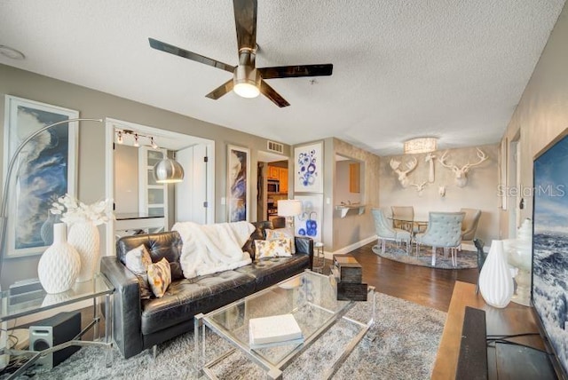 living room with ceiling fan, dark hardwood / wood-style floors, and a textured ceiling