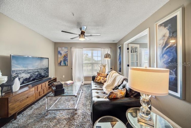 living room featuring ceiling fan and a textured ceiling