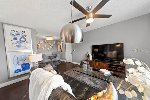 living room with dark hardwood / wood-style flooring, ceiling fan, and a textured ceiling