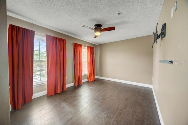 unfurnished room with ceiling fan, dark hardwood / wood-style flooring, a textured ceiling, and a wealth of natural light