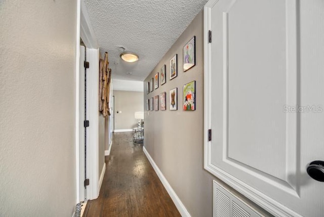 corridor featuring dark wood-type flooring and a textured ceiling