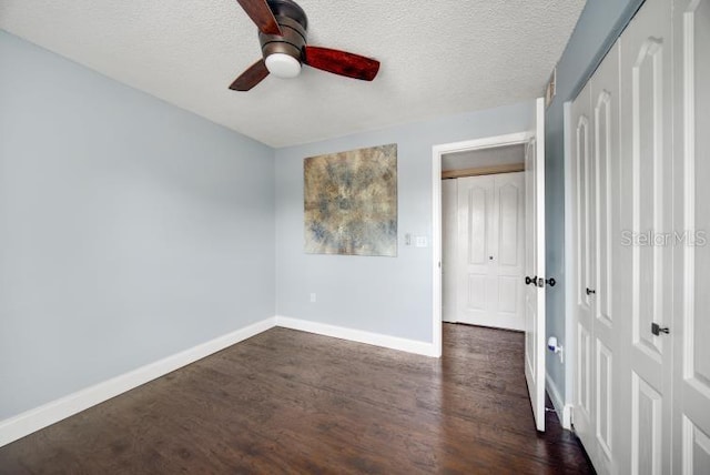 unfurnished bedroom featuring a textured ceiling, dark wood-type flooring, and ceiling fan