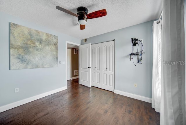 unfurnished bedroom featuring ceiling fan, dark hardwood / wood-style flooring, a closet, and a textured ceiling