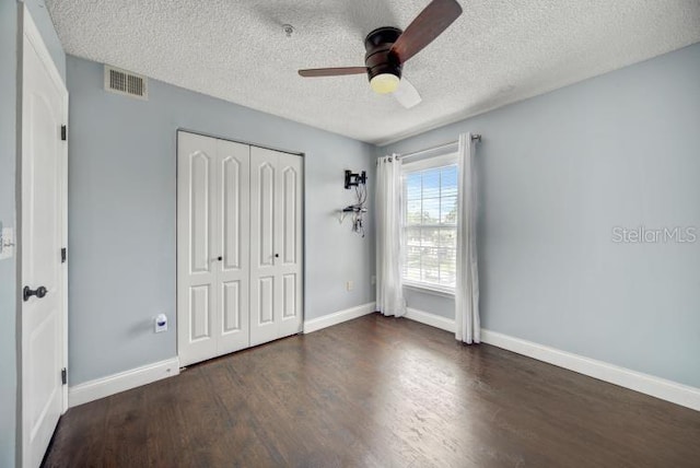 unfurnished bedroom featuring dark hardwood / wood-style floors, a textured ceiling, ceiling fan, and a closet