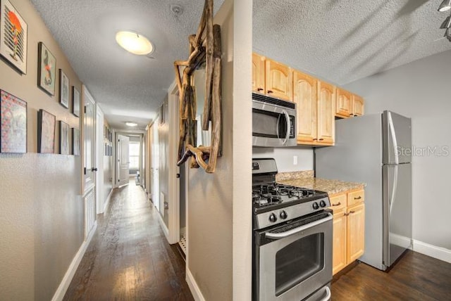 kitchen featuring dark wood-type flooring, light brown cabinetry, a textured ceiling, appliances with stainless steel finishes, and light stone countertops