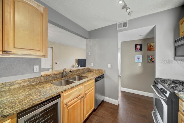 kitchen with sink, appliances with stainless steel finishes, beverage cooler, dark stone counters, and light brown cabinets