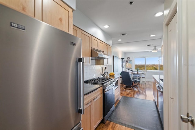 kitchen featuring stainless steel appliances, light brown cabinetry, and hardwood / wood-style floors