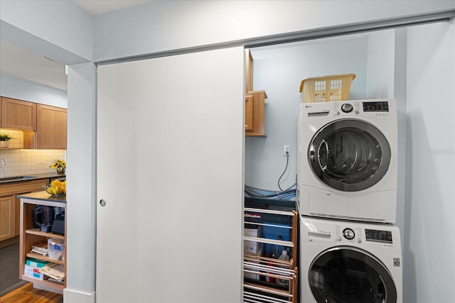 laundry area with stacked washer and dryer, hardwood / wood-style flooring, and sink