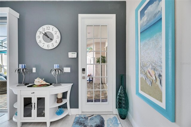 doorway with baseboards and tile patterned floors