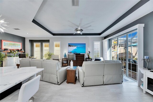 living room featuring a wealth of natural light, a tray ceiling, and visible vents