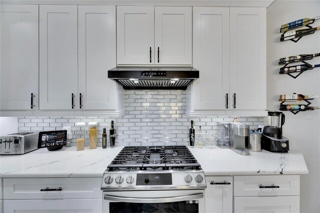 kitchen featuring light stone counters, stainless steel range with gas stovetop, ventilation hood, white cabinetry, and backsplash