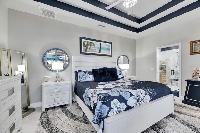 bedroom featuring baseboards, visible vents, and a tray ceiling