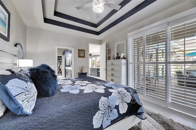 bedroom featuring a walk in closet, ceiling fan, and a raised ceiling