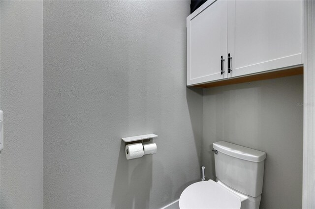 bathroom with toilet and a textured wall