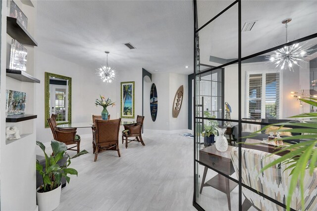 dining room with light wood-type flooring, visible vents, and an inviting chandelier