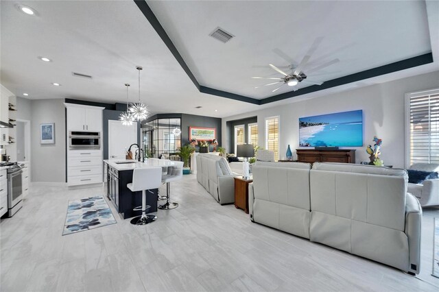 living area featuring plenty of natural light, visible vents, a raised ceiling, and recessed lighting