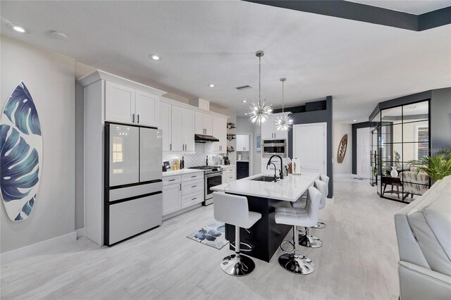 kitchen featuring stainless steel stove, a sink, white cabinets, light countertops, and freestanding refrigerator