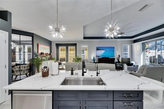 kitchen with open floor plan, a sink, a kitchen island with sink, and an inviting chandelier