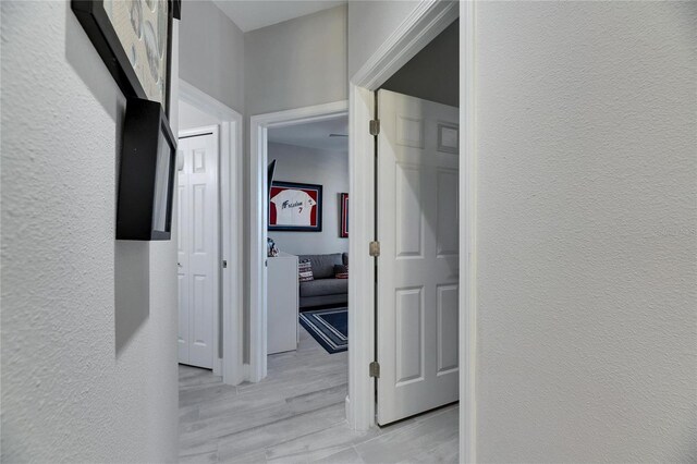 hallway featuring a textured wall and light wood-type flooring