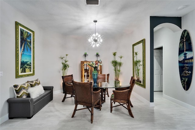 dining room with arched walkways, visible vents, a notable chandelier, and baseboards