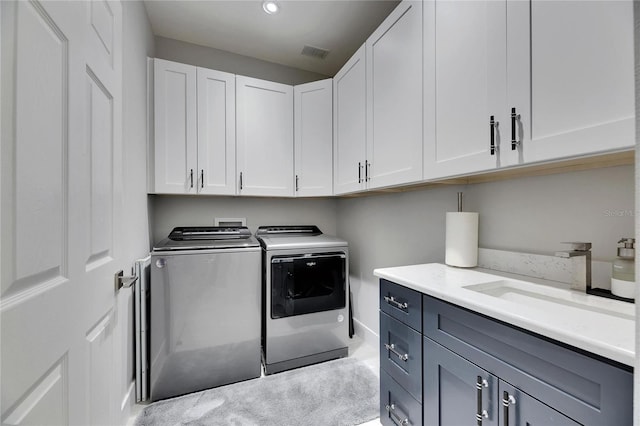 laundry room featuring cabinet space, a sink, visible vents, and separate washer and dryer