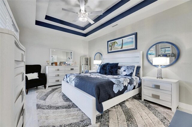 bedroom featuring ceiling fan, a raised ceiling, visible vents, and baseboards