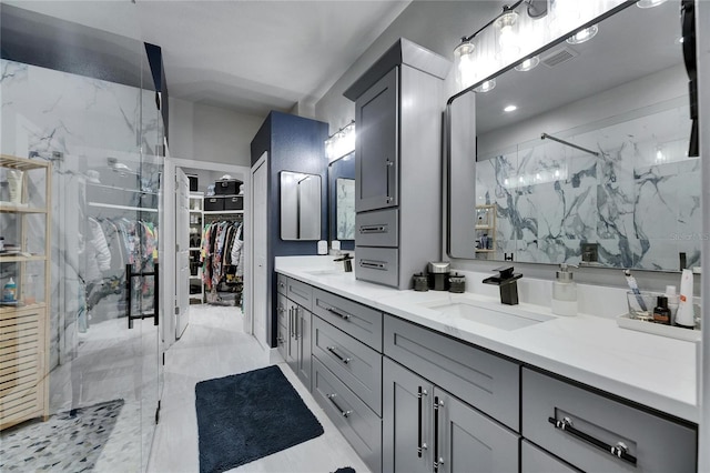 full bathroom featuring a sink, visible vents, a marble finish shower, double vanity, and a walk in closet