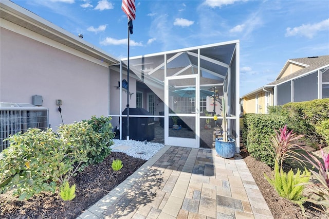 entrance to property with central air condition unit, a patio area, and stucco siding