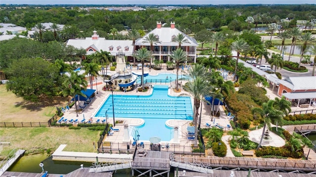 community pool featuring a boat dock, a water view, and fence