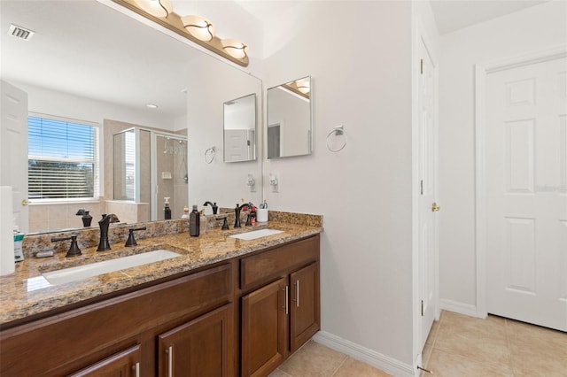 bathroom with a shower with door, vanity, and tile patterned floors