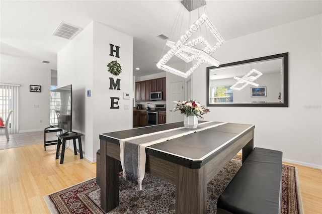 dining area with a healthy amount of sunlight, a notable chandelier, and light hardwood / wood-style flooring