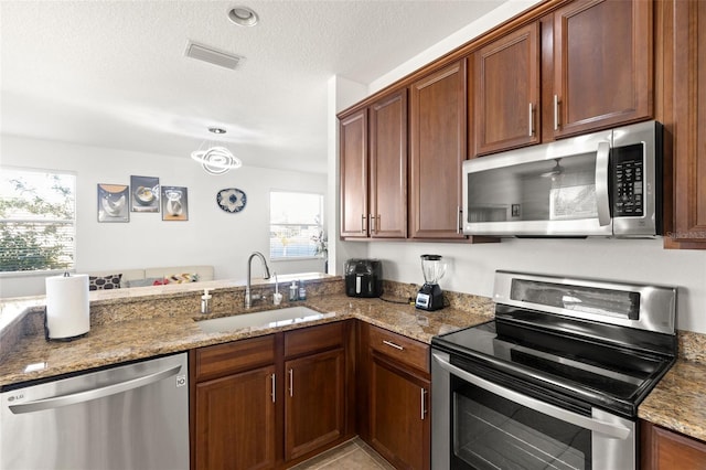 kitchen featuring stainless steel appliances, light stone countertops, sink, and plenty of natural light