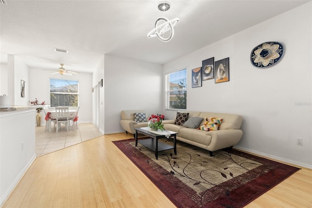 living room featuring a wealth of natural light, ceiling fan, and light hardwood / wood-style flooring