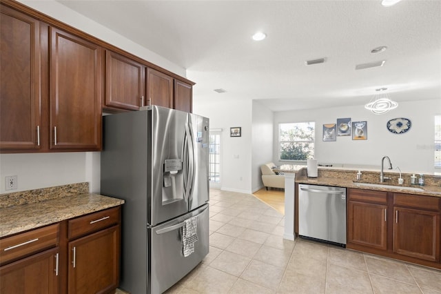 kitchen with light stone counters, sink, light tile patterned floors, and stainless steel appliances