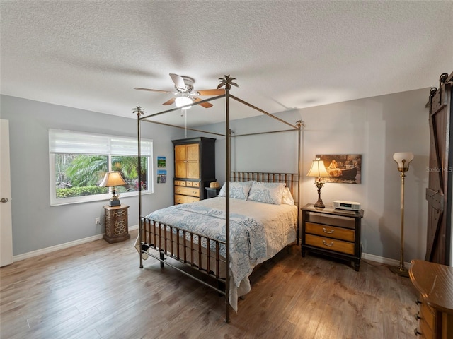 bedroom with a textured ceiling, dark wood-type flooring, and ceiling fan