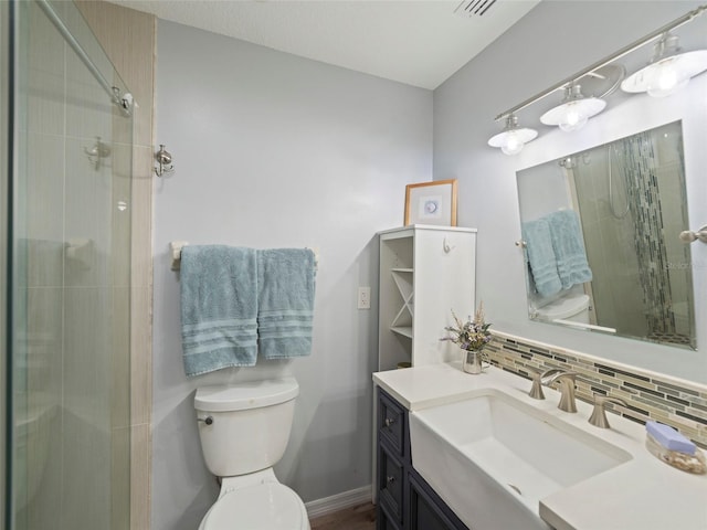 bathroom featuring tasteful backsplash, vanity, an enclosed shower, and toilet