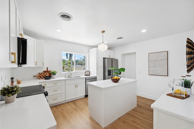 kitchen with pendant lighting, white cabinetry, sink, a center island, and stainless steel appliances