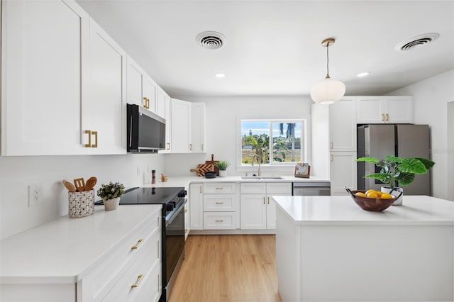 kitchen featuring sink, light hardwood / wood-style flooring, hanging light fixtures, stainless steel appliances, and white cabinets