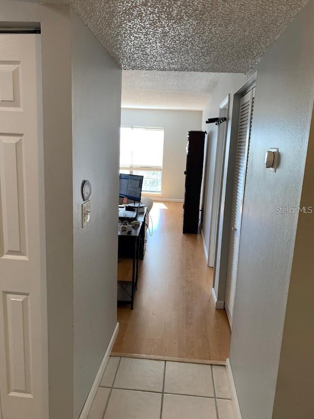 hall with light tile patterned floors and a textured ceiling