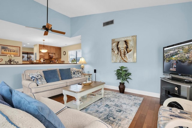 living room with dark wood-type flooring, ceiling fan, and vaulted ceiling