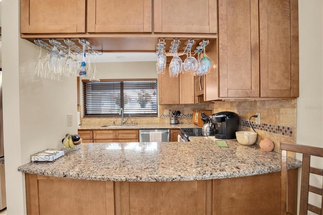 kitchen featuring tasteful backsplash, sink, light stone counters, and appliances with stainless steel finishes