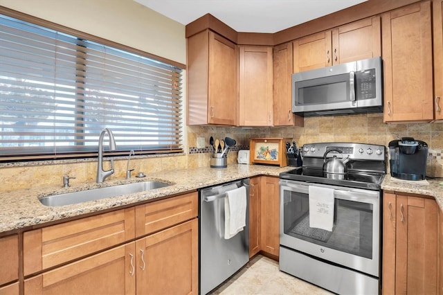 kitchen featuring sink, backsplash, stainless steel appliances, and light stone countertops