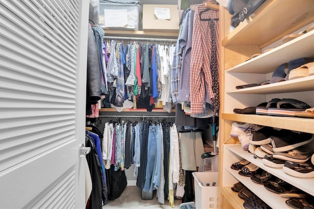 walk in closet with light tile patterned floors