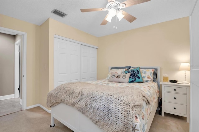 bedroom with light carpet, ceiling fan, and a closet