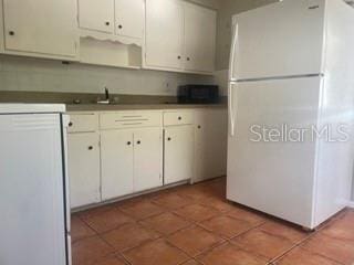 kitchen featuring sink, mail boxes, white cabinets, dark tile patterned flooring, and white fridge