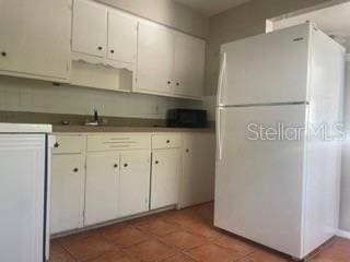 kitchen featuring white refrigerator, dark tile patterned floors, mail boxes, and white cabinets