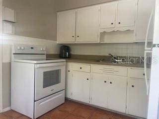 kitchen featuring white cabinetry, white appliances, sink, and dark tile patterned floors