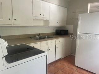 kitchen with sink, tile patterned floors, white cabinets, and white fridge