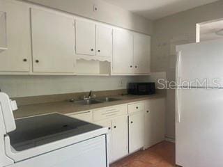 kitchen featuring white cabinetry, range, sink, and white refrigerator