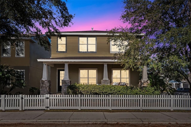 view of front facade with covered porch, a fenced front yard, and stucco siding